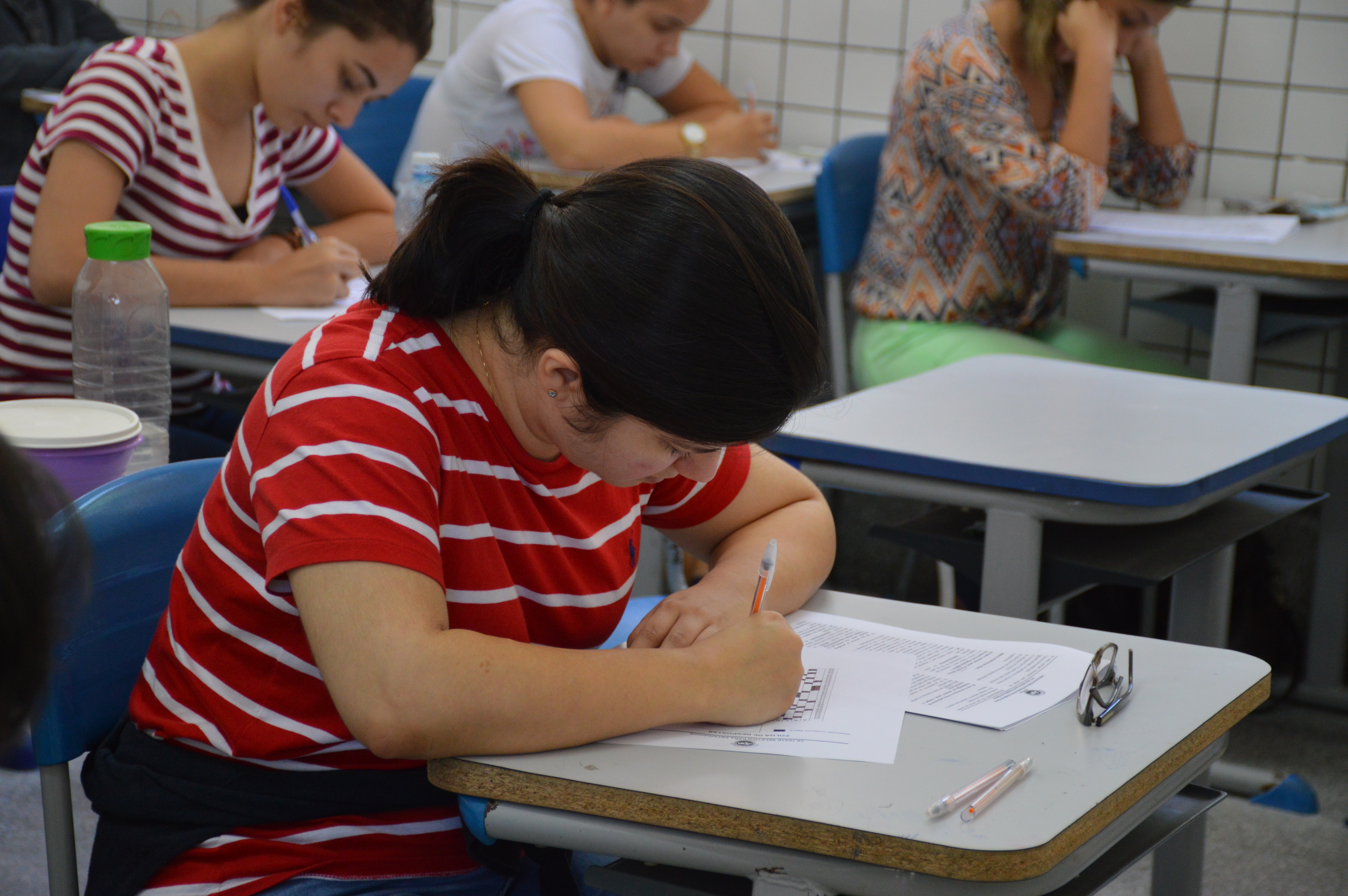 Estudante de camisa listrada concentrada fazendo a prova do Processo Seletivo para estagiários de Direito da DPE/RN
